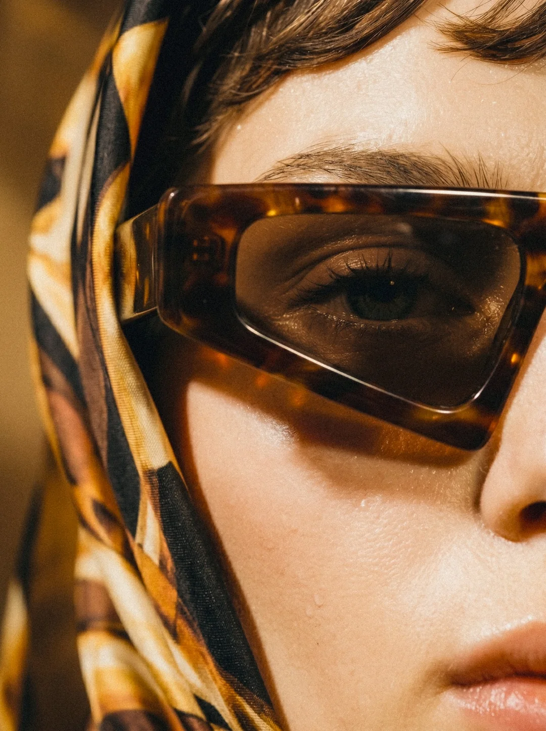 AI fashion campaign visual: tortoiseshell sunglasses, silk scarf and warm stone