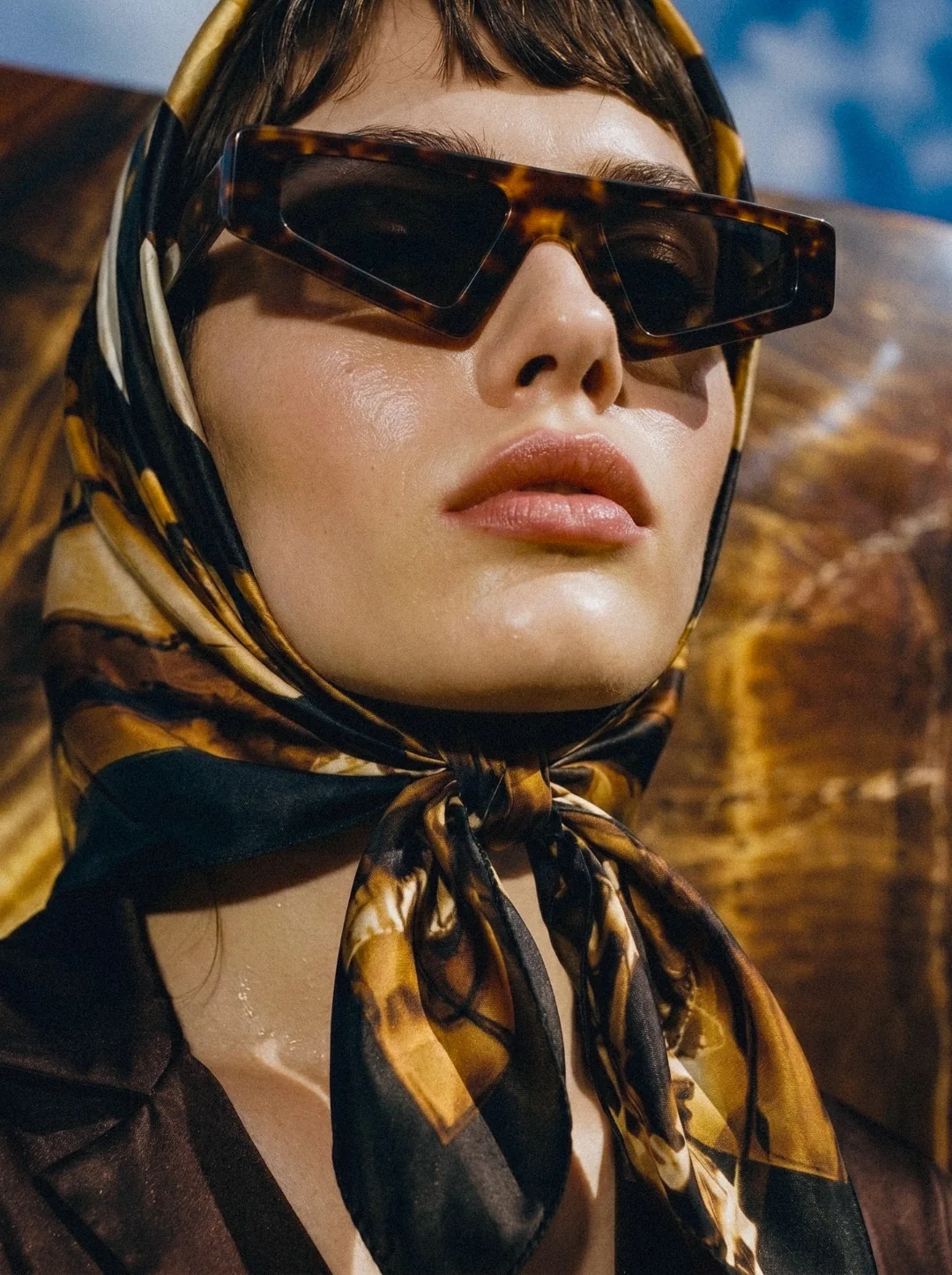 AI fashion campaign visual: sunglasses and silk scarf against amber marble