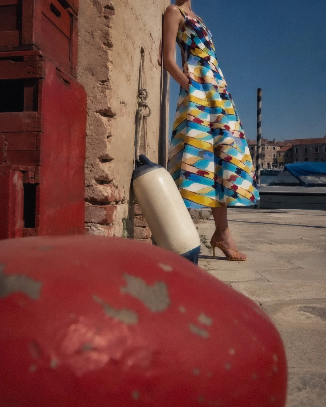AI fashion campaign visual: model in colourful printed dress walking past Venetian glass