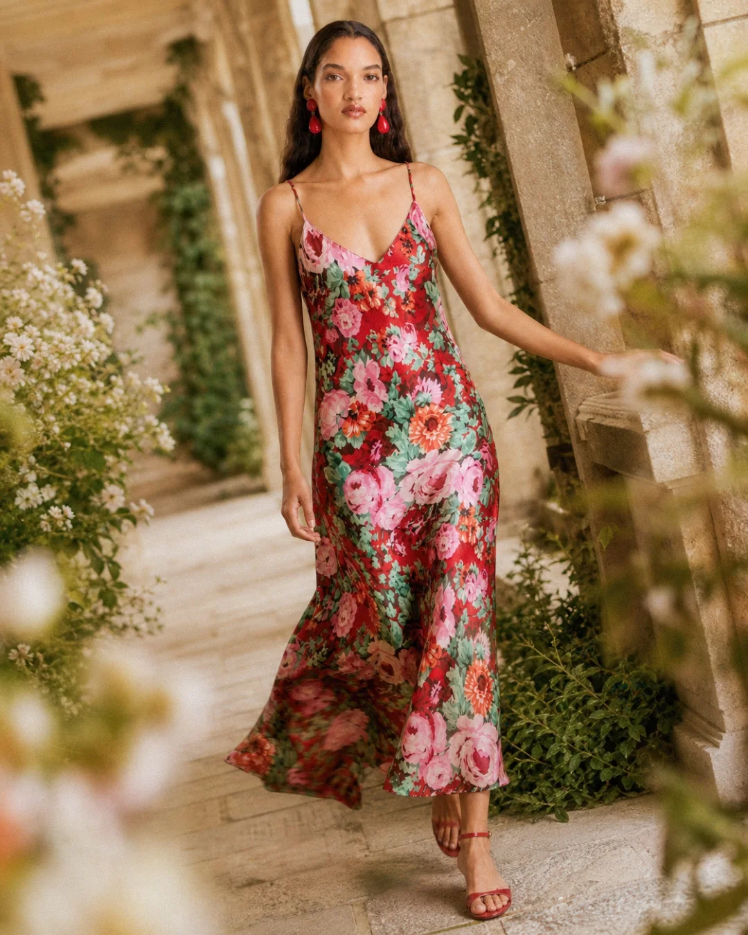 AI fashion campaign visual: model resting among roses in a red floral dress